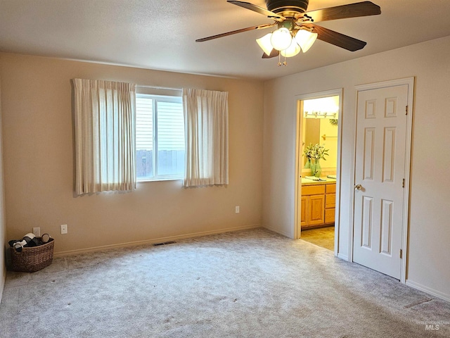 unfurnished bedroom with light carpet, connected bathroom, and ceiling fan