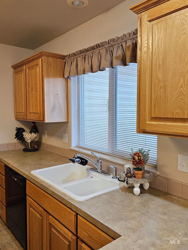 kitchen featuring light tile patterned floors, black dishwasher, and sink