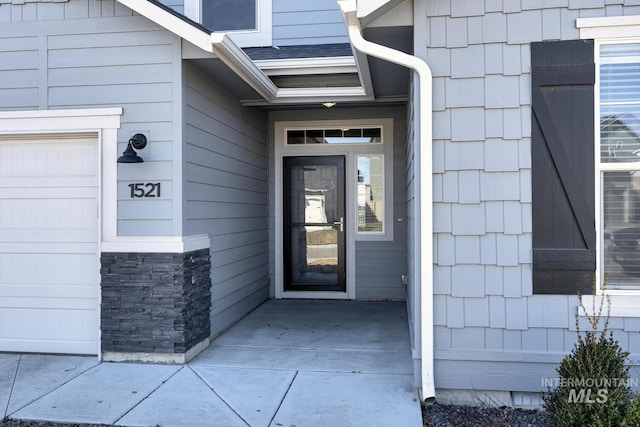 property entrance with an attached garage and roof with shingles