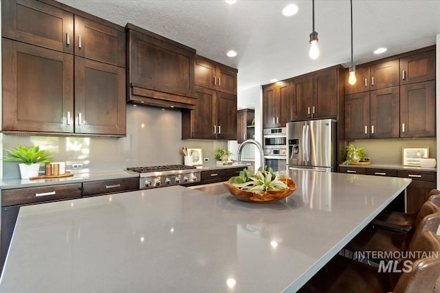 5085 S Taboo Pl, Boise, ID 83716 - kitchen with appliances with stainless steel finishes, a breakfast bar, dark brown cabinets, pendant lighting, and light countertops