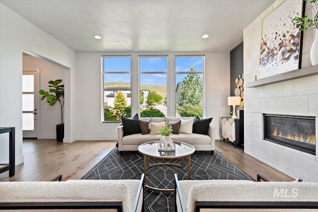 5085 S Taboo Pl, Boise, ID 83716 - living room with wood finished floors, a tile fireplace, a textured ceiling, recessed lighting, and baseboards
