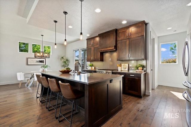 5085 S Taboo Pl, Boise, ID 83716 - kitchen with baseboards, a textured ceiling, a kitchen bar, a sink, and an island with sink