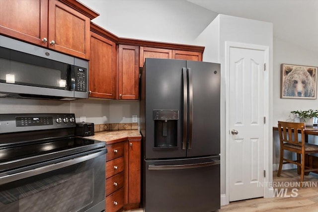 kitchen featuring black appliances, light countertops, light wood-style floors, and brown cabinetry