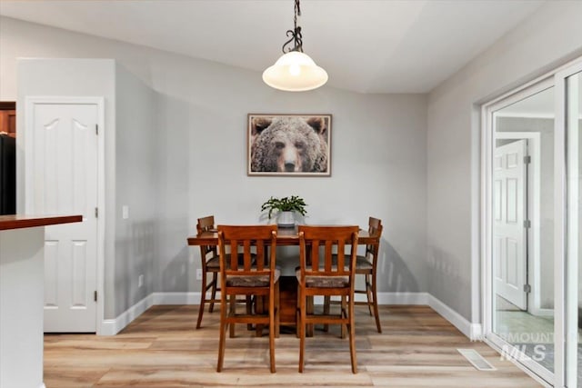 dining space with light wood-style flooring and baseboards