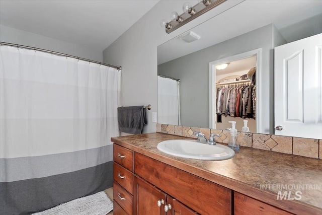 full bathroom featuring a walk in closet and vanity