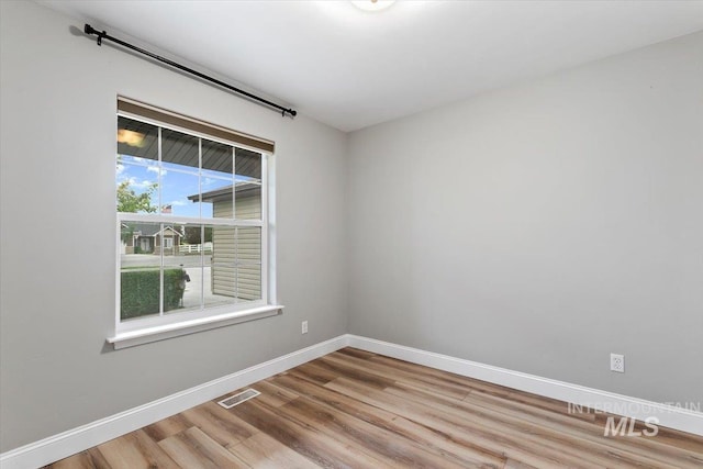 spare room with visible vents, baseboards, and wood finished floors