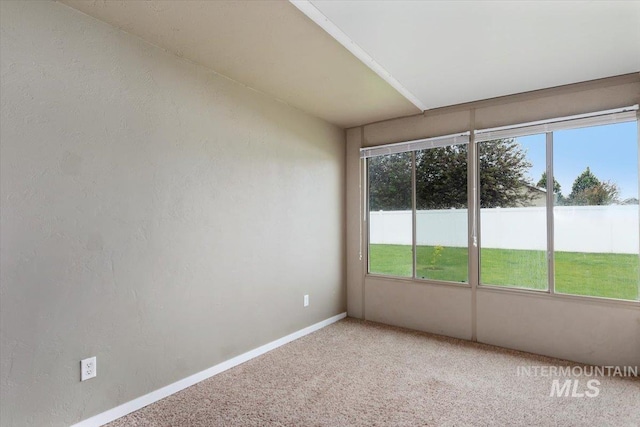 interior space with light carpet, a textured wall, and baseboards