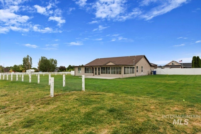 rear view of property with a sunroom, a fenced backyard, and a yard