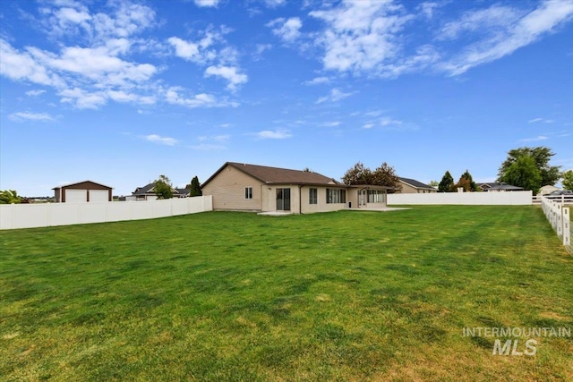 rear view of property featuring a lawn and a fenced backyard