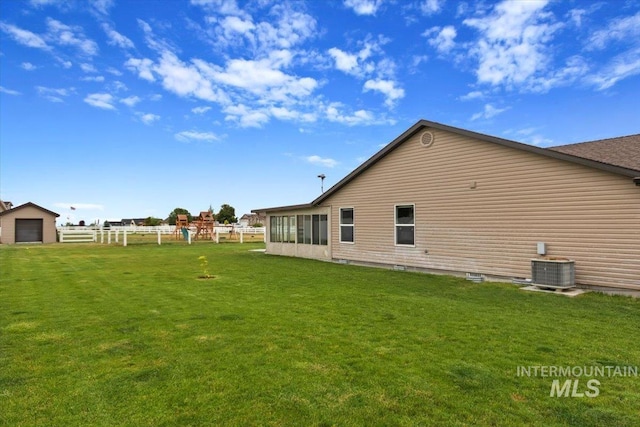 rear view of house with a lawn, cooling unit, and fence