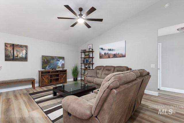 living area with lofted ceiling, ceiling fan, wood finished floors, and baseboards