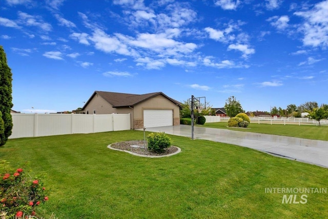 view of yard with driveway, an attached garage, and fence