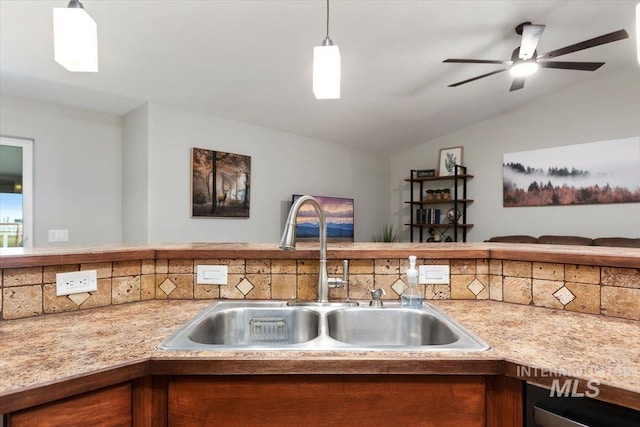 kitchen featuring brown cabinets, lofted ceiling, light countertops, open floor plan, and a sink