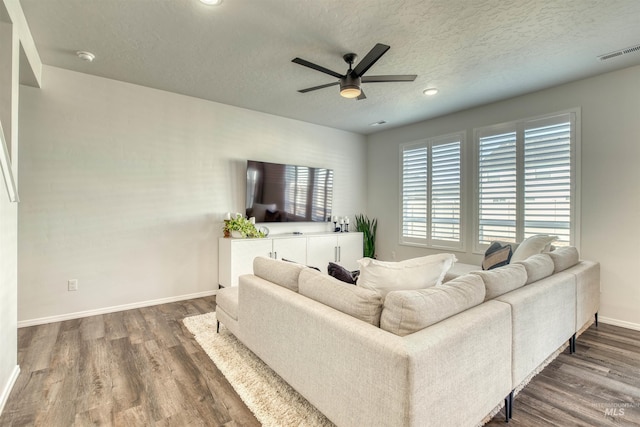 living room featuring visible vents, a ceiling fan, a textured ceiling, wood finished floors, and baseboards