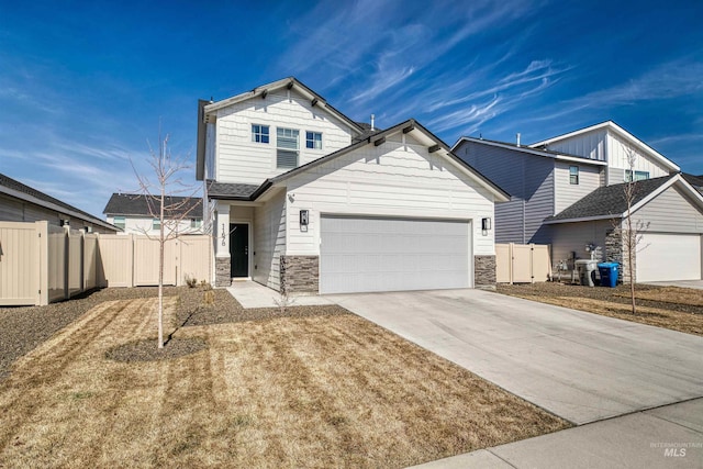 view of front of property featuring an attached garage, fence, stone siding, driveway, and a gate