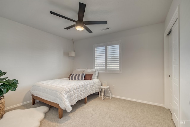 bedroom featuring visible vents, baseboards, light carpet, a closet, and a ceiling fan