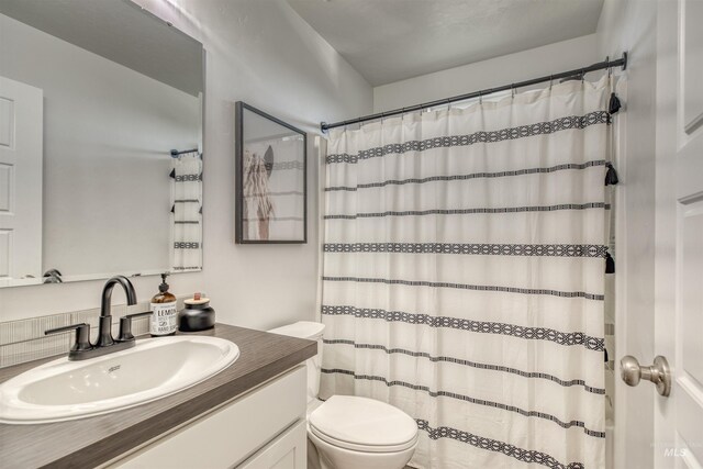 bathroom featuring a shower with shower curtain, toilet, and vanity