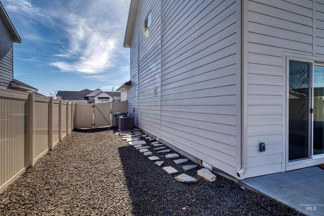 view of property exterior with cooling unit, fence, and a gate