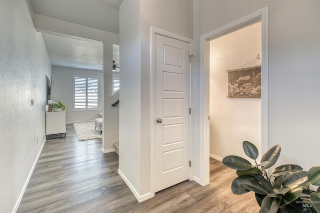 corridor featuring stairs, wood finished floors, and baseboards