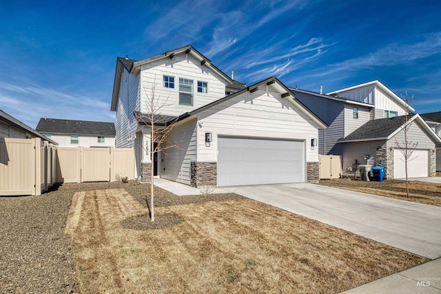 view of front of home with a gate, stone siding, fence, concrete driveway, and an attached garage