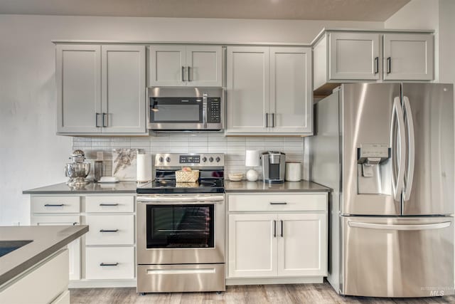 kitchen with stainless steel appliances, tasteful backsplash, gray cabinetry, and light wood finished floors