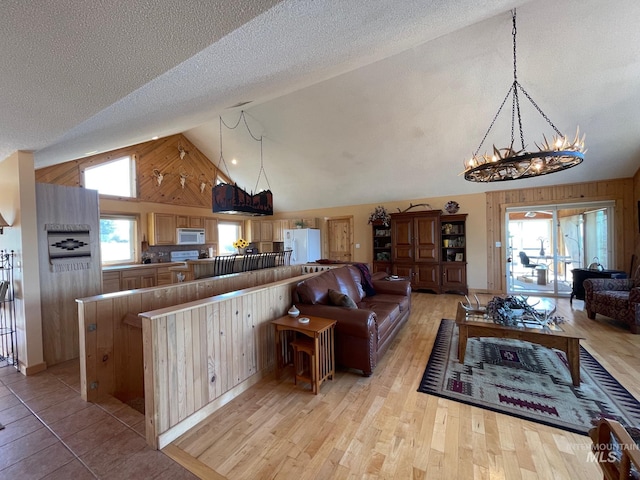 living room with light hardwood / wood-style floors, high vaulted ceiling, and a textured ceiling