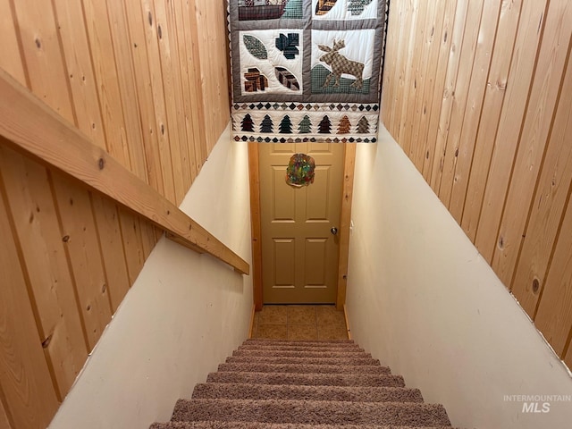 stairs featuring wooden walls and tile patterned flooring