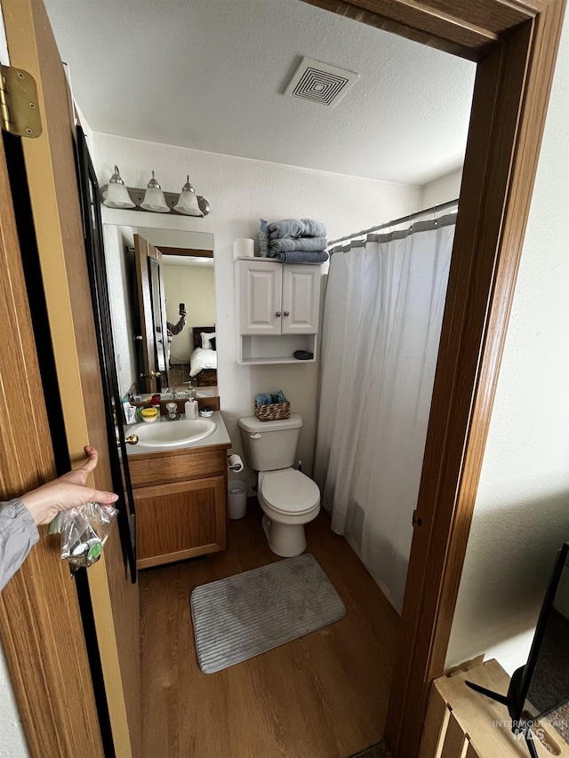 full bathroom with visible vents, vanity, wood finished floors, toilet, and a shower with curtain