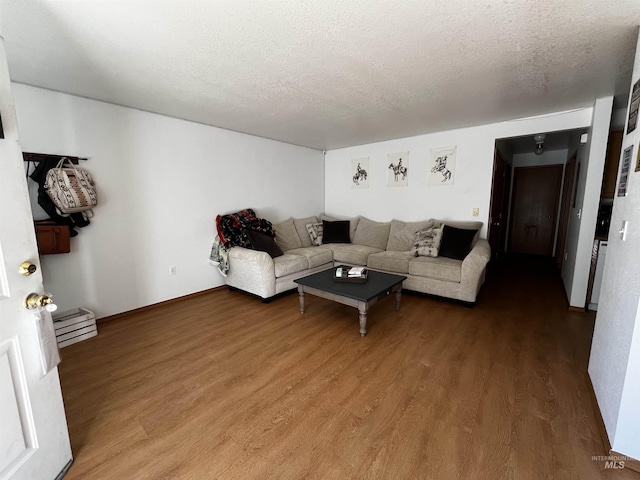 living area with baseboards, a textured ceiling, a baseboard heating unit, and wood finished floors