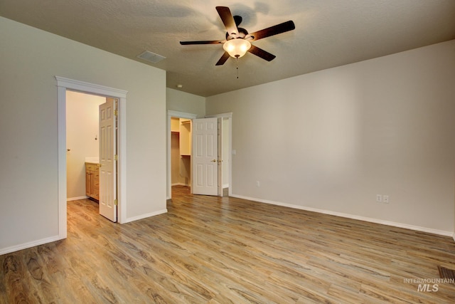 2853 N High Desert Way, Meridian, ID 83646 - unfurnished bedroom with light wood finished floors, a spacious closet, baseboards, ensuite bathroom, and a ceiling fan