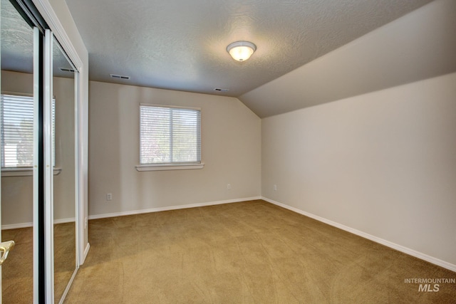 2853 N High Desert Way, Meridian, ID 83646 - additional living space with light carpet, a textured ceiling, vaulted ceiling, and baseboards