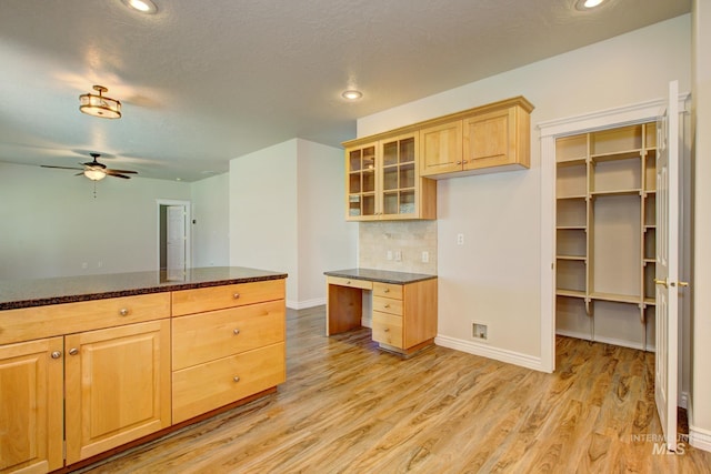 2853 N High Desert Way, Meridian, ID 83646 - kitchen featuring light wood finished floors, light brown cabinets, ceiling fan, glass insert cabinets, and decorative backsplash