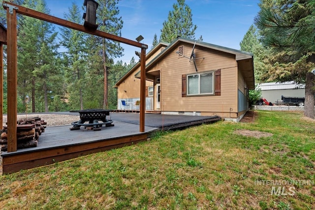 rear view of property with a wooden deck and a yard