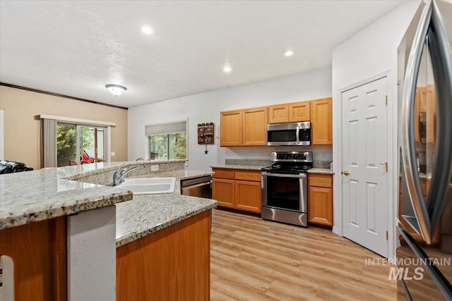 kitchen with sink, light hardwood / wood-style flooring, stainless steel appliances, light stone countertops, and a textured ceiling