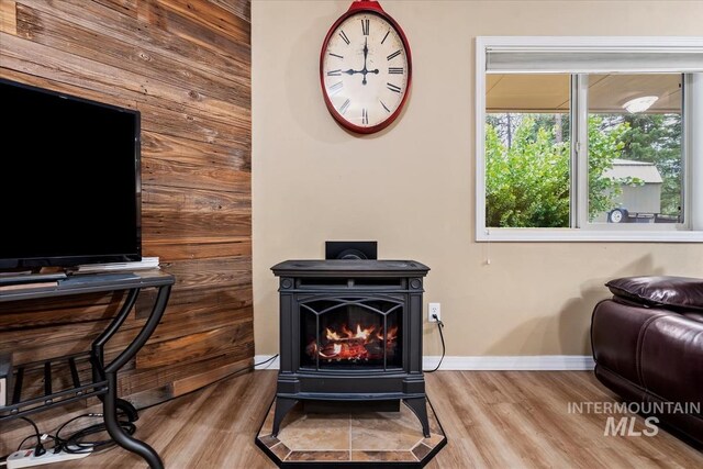 interior space with hardwood / wood-style floors, wooden walls, and a wood stove