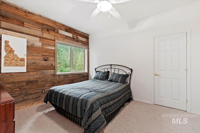 carpeted bedroom with ceiling fan and wooden walls