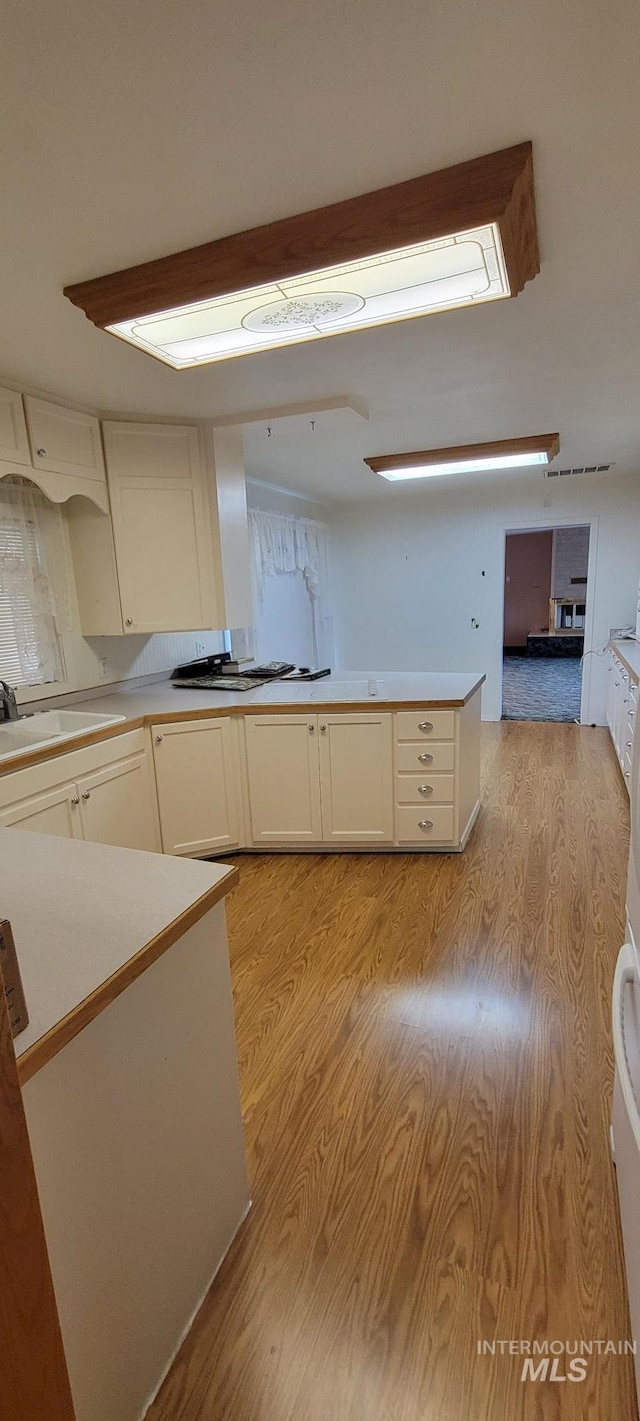 kitchen with white cabinets, light countertops, light wood-style flooring, and a sink