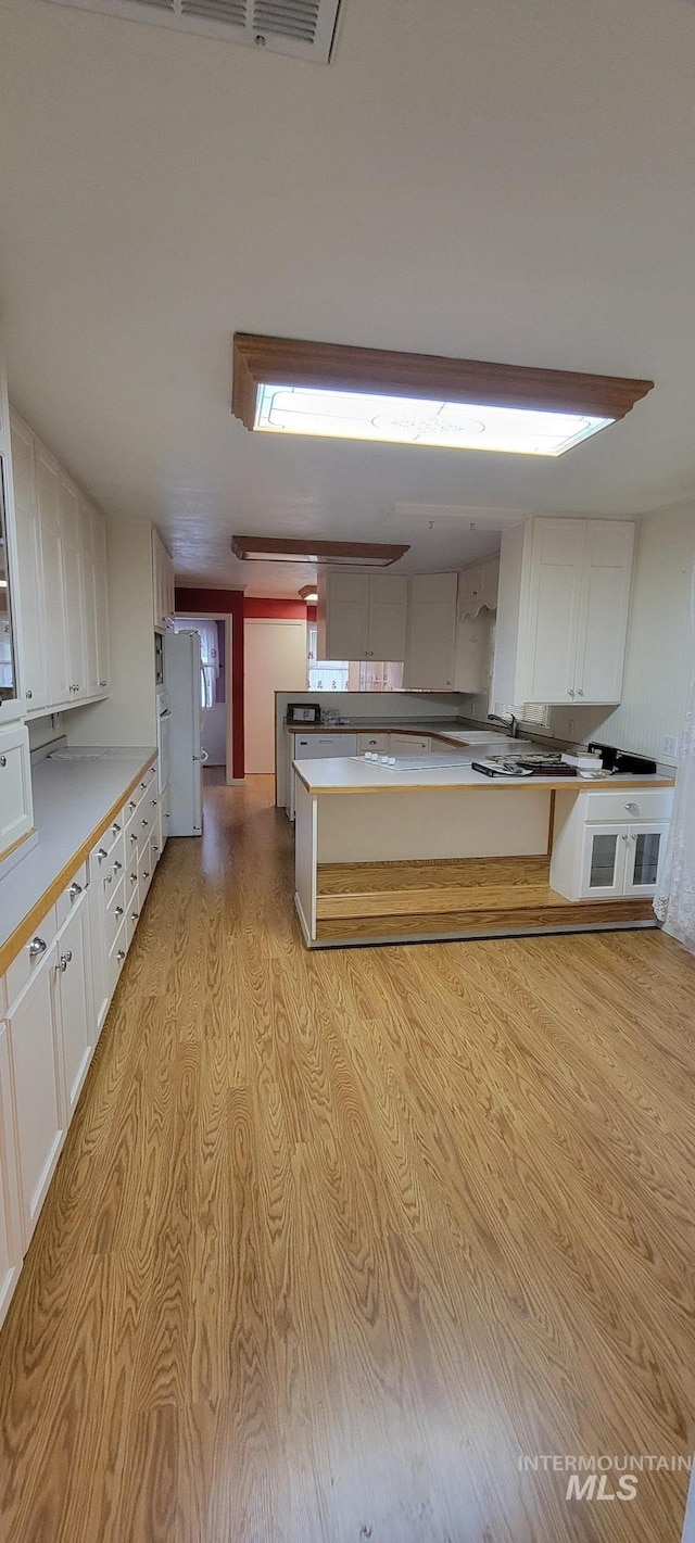 kitchen with white cabinetry, light countertops, and light wood-type flooring