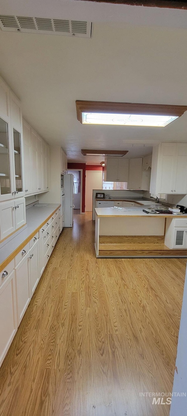 kitchen featuring white cabinets, glass insert cabinets, light countertops, and freestanding refrigerator