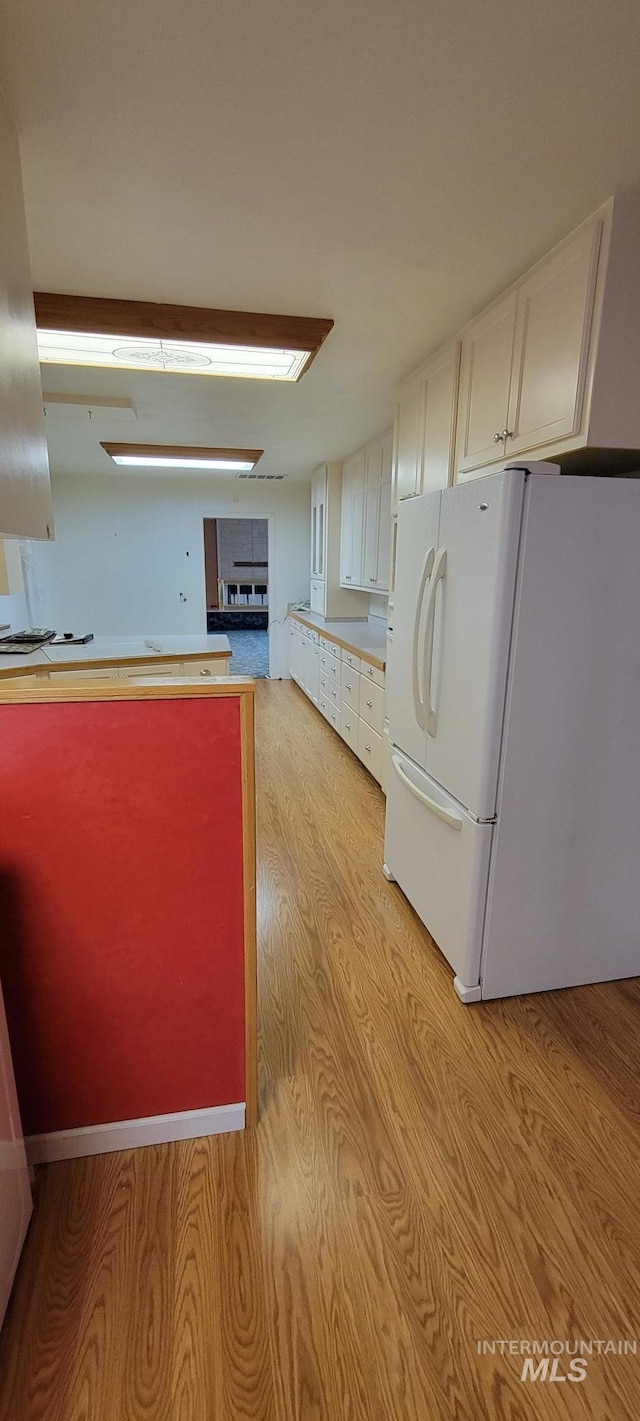 kitchen featuring freestanding refrigerator, light wood-type flooring, and white cabinetry