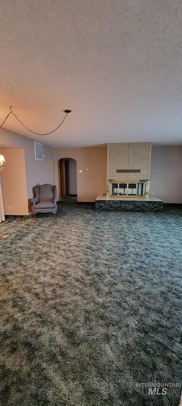 unfurnished living room with arched walkways, an inviting chandelier, a textured ceiling, and carpet