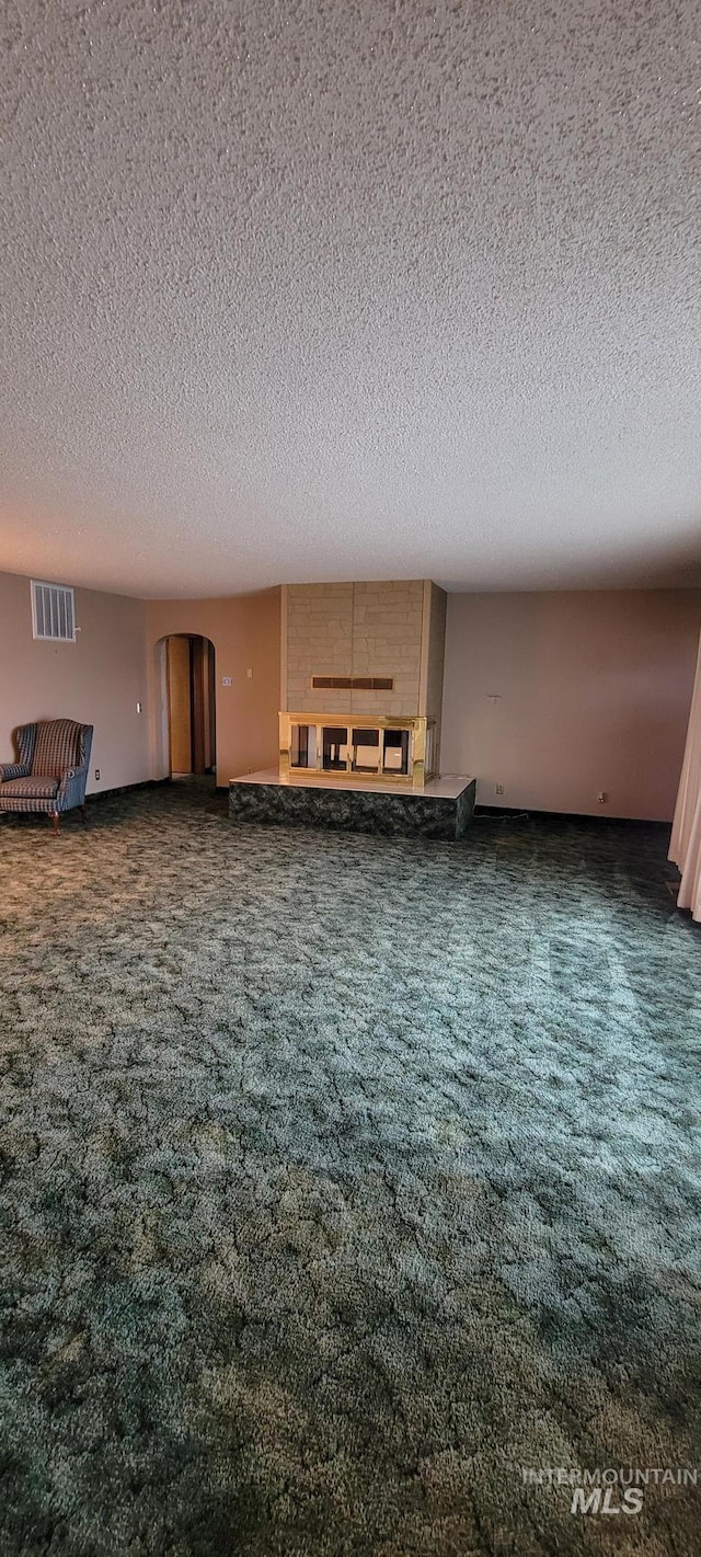 interior space featuring arched walkways, carpet flooring, a textured ceiling, and visible vents
