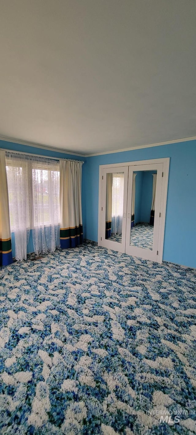 unfurnished bedroom with french doors, carpet flooring, ornamental molding, and multiple windows