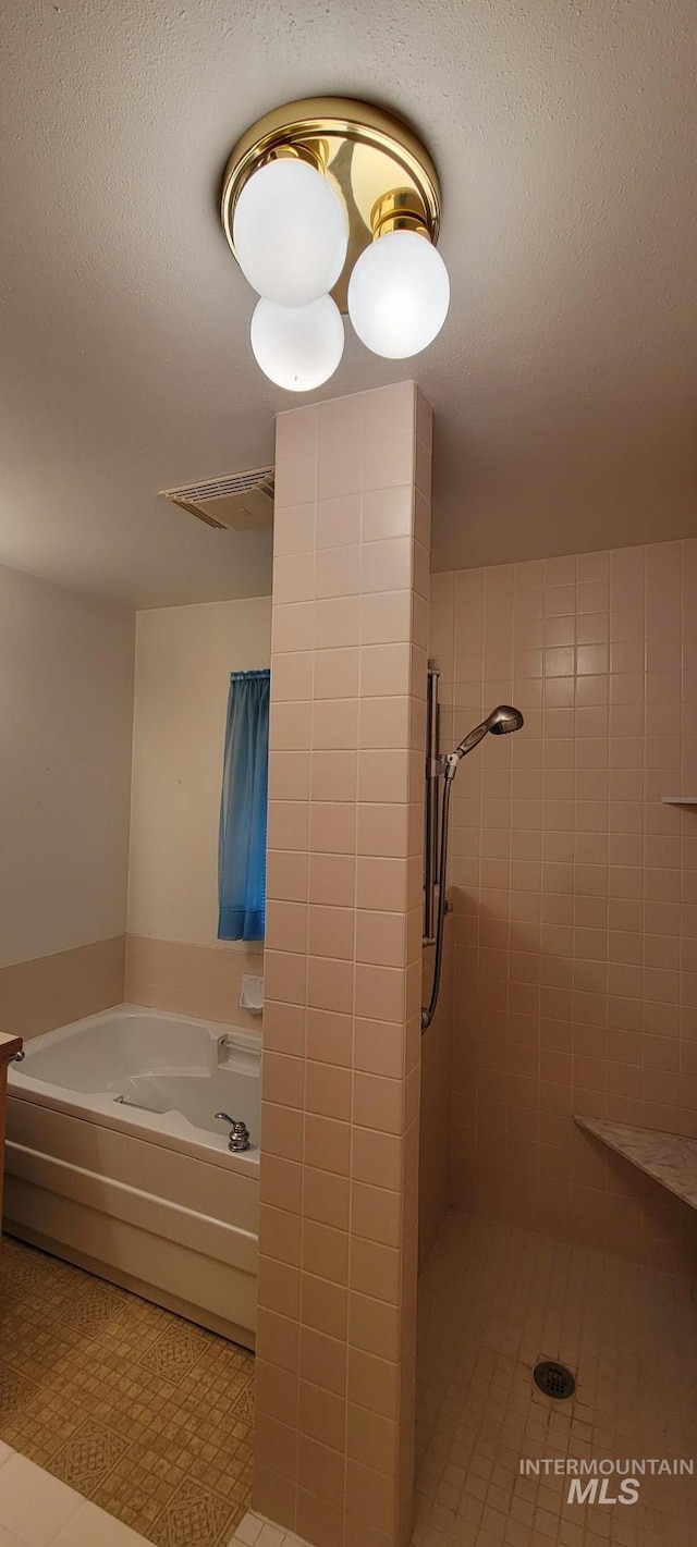 full bathroom featuring a bath, visible vents, tile patterned flooring, and a tile shower