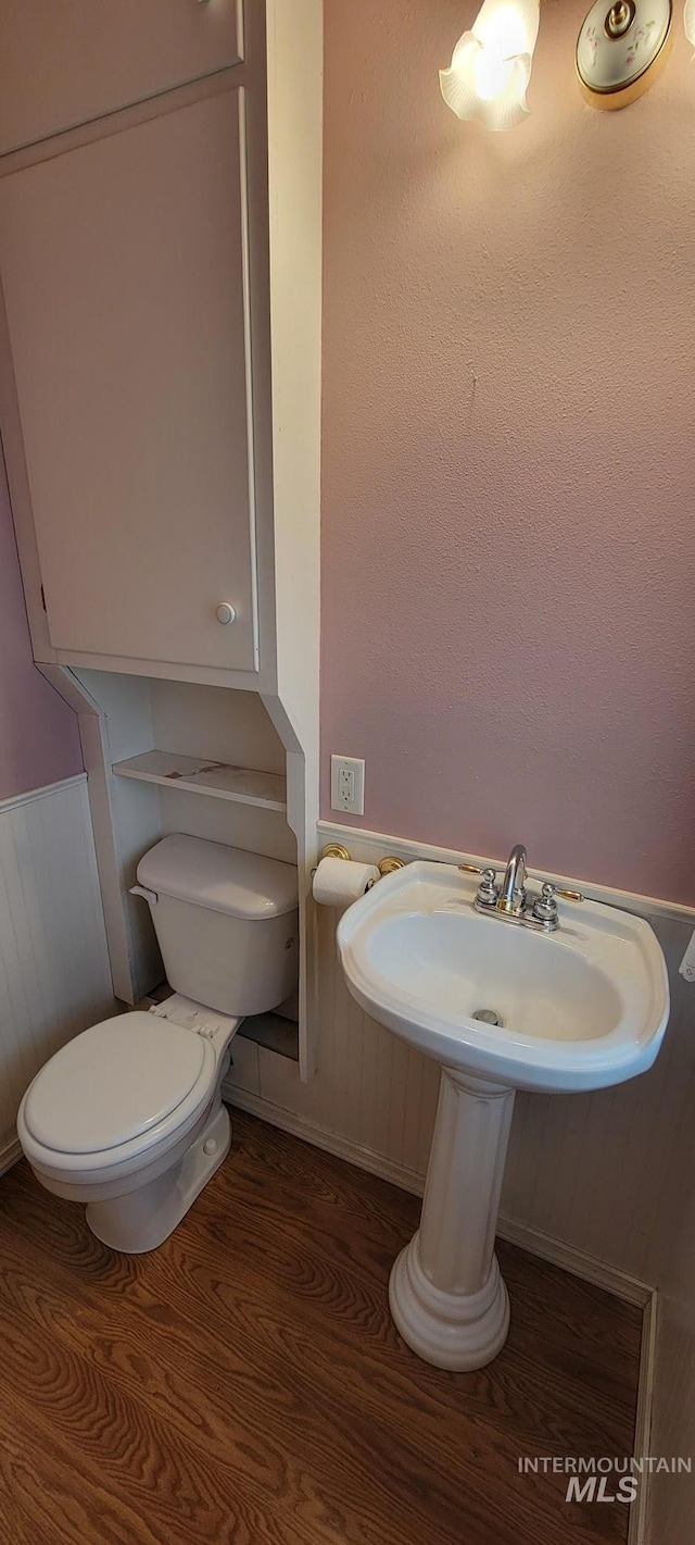bathroom with wood finished floors, a wainscoted wall, and toilet