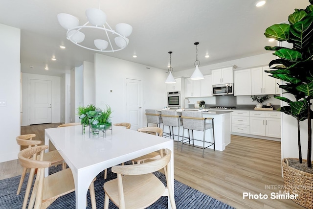 dining space with light hardwood / wood-style floors and an inviting chandelier