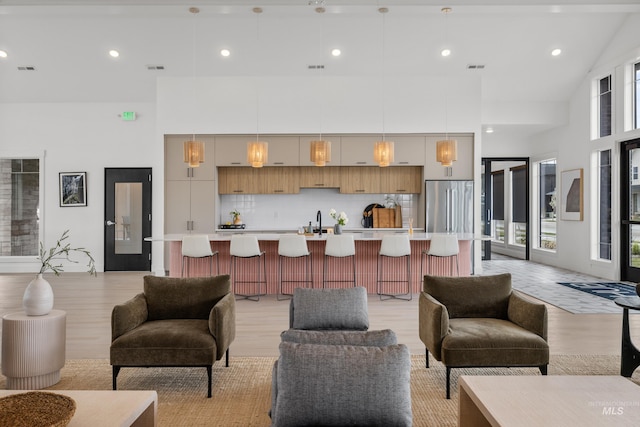 living room featuring a towering ceiling and light hardwood / wood-style flooring