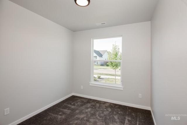 empty room featuring dark carpet and a healthy amount of sunlight