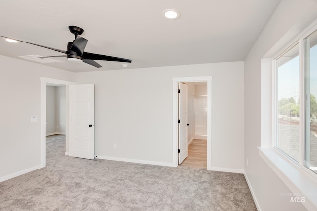 unfurnished bedroom featuring light carpet, ensuite bath, and ceiling fan