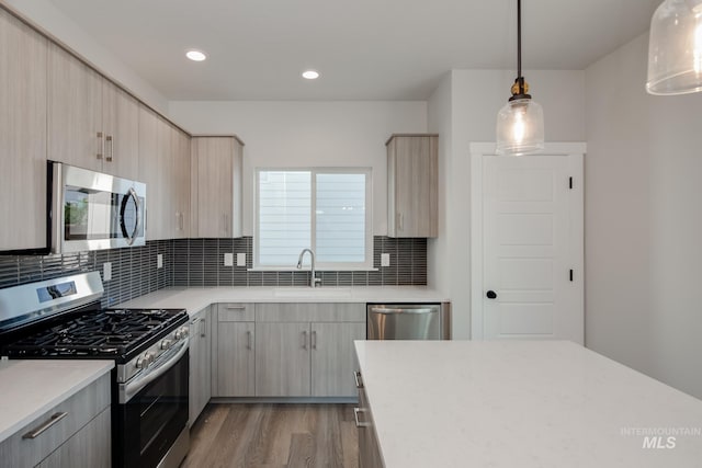 kitchen featuring decorative light fixtures, light brown cabinetry, and appliances with stainless steel finishes